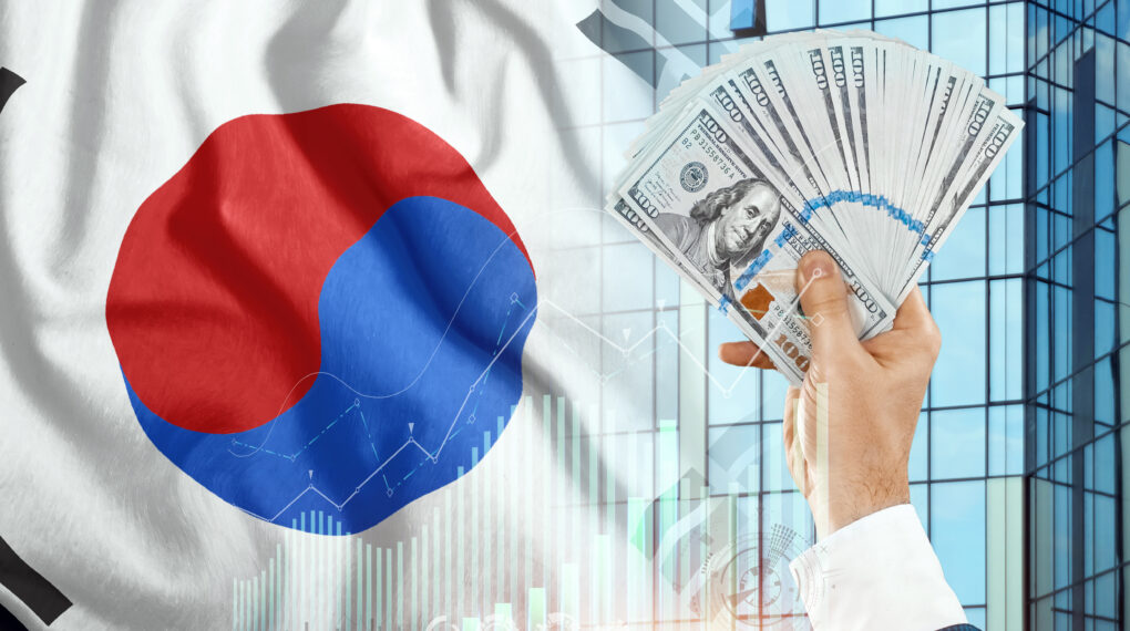 Money in a man's hand against the background of the flag of South Korea. Income of Koreans. Financial condition of South Koreans, taxes, loans, mortgages. State debt of the country