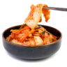 Kimchi cabbage in a bowl with chopsticks on white background, top view, Korean food