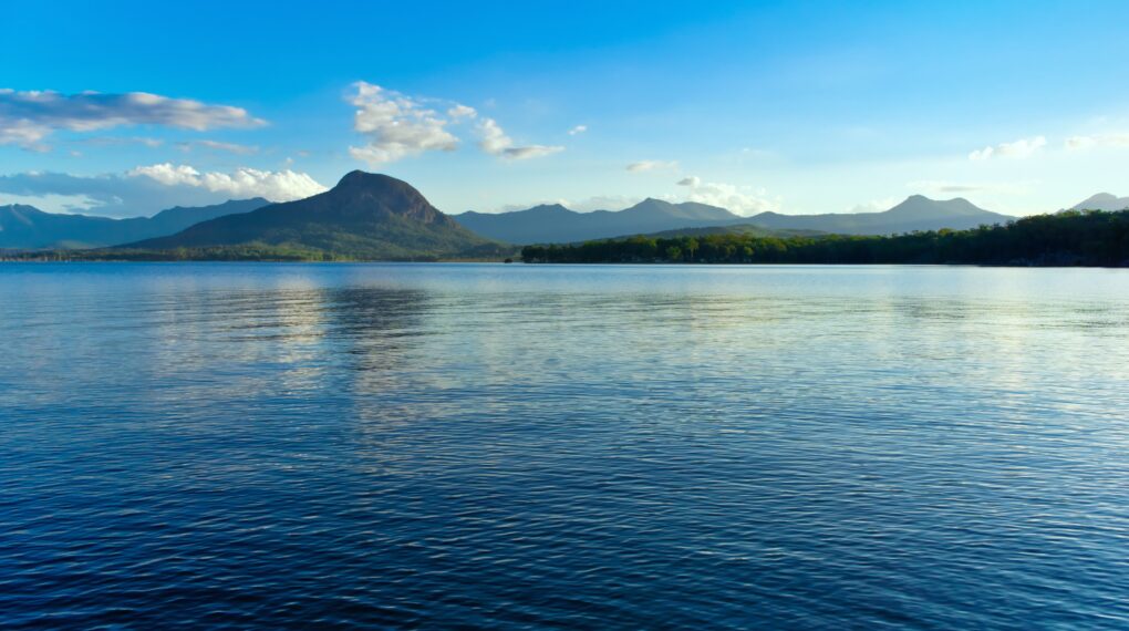A panoramic shot of a tranquil lake toba reflecting the blue sky